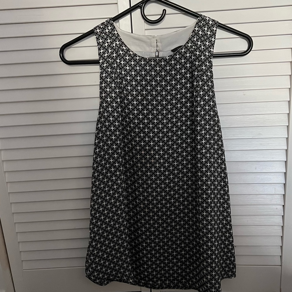 Black and white sleeveless blouse with buttoned back and sheer lining